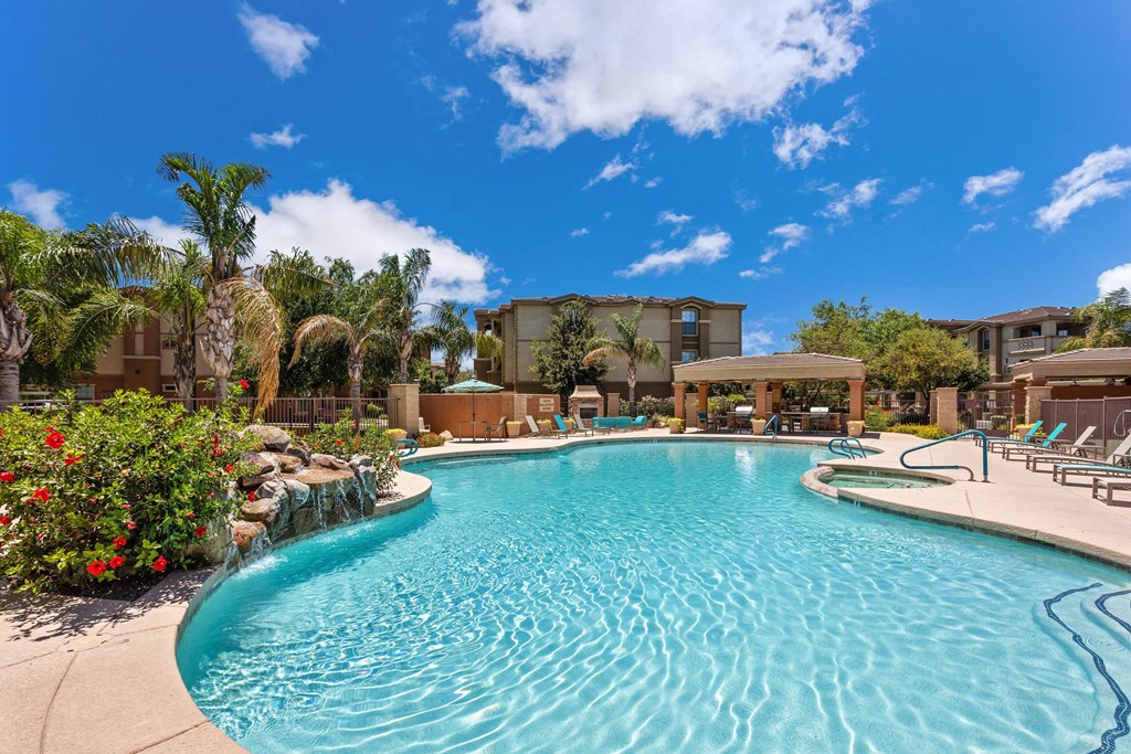 A swimming pool surrounded by palm trees and red flowers.