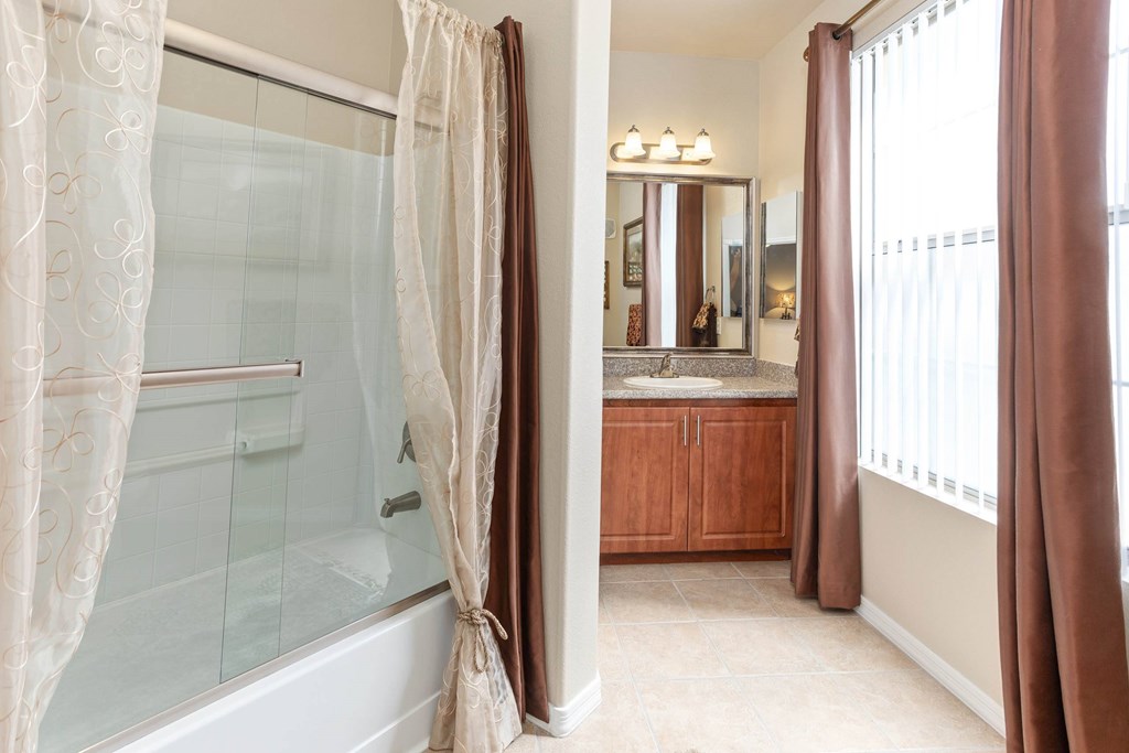 A bathroom with a large mirror and a bathtub with a shower curtain.