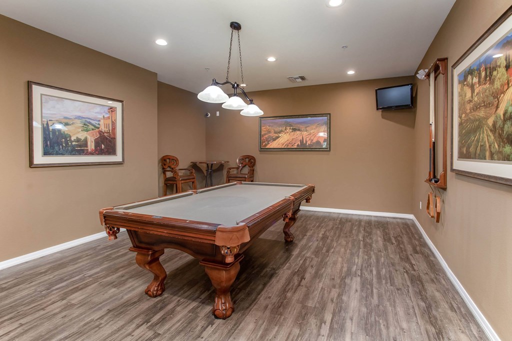 A pool table in a room with brown walls and wooden flooring.