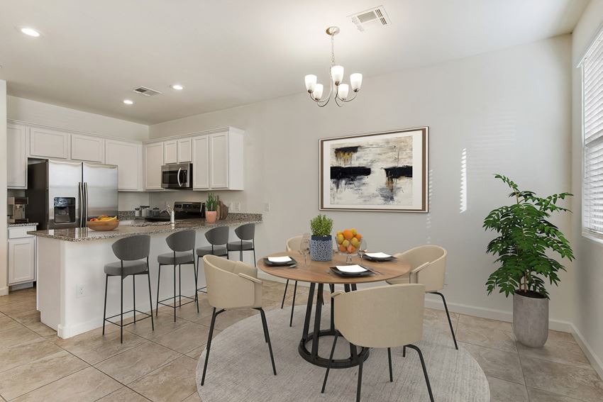 Dining area and kitchen with room for bar top seating dining area with circular table and four seats. four barstools line the kitchen countertop