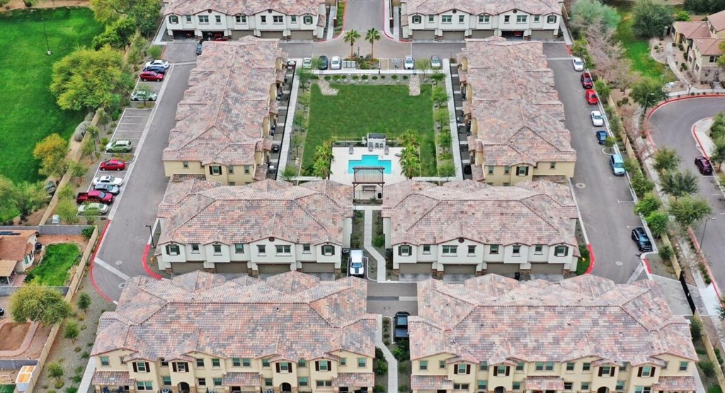 Aerial view of Casa Sole Vita apartment community showing 8 apartment buildings, grassy playfield, pool and parking.