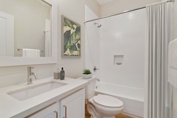 A white bathroom with a toilet, sink, and shower.
