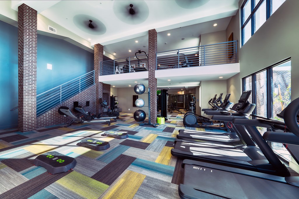 a gym with treadmills and weights in a large room with windows a gym with treadmills and weights in a large room with windows at Elevation at the Village, Arizona, 85295