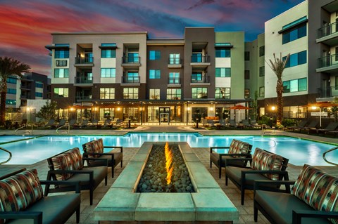 a swimming pool at night with an apartment building in the background at Elevation at the Village, Gilbert, 85295