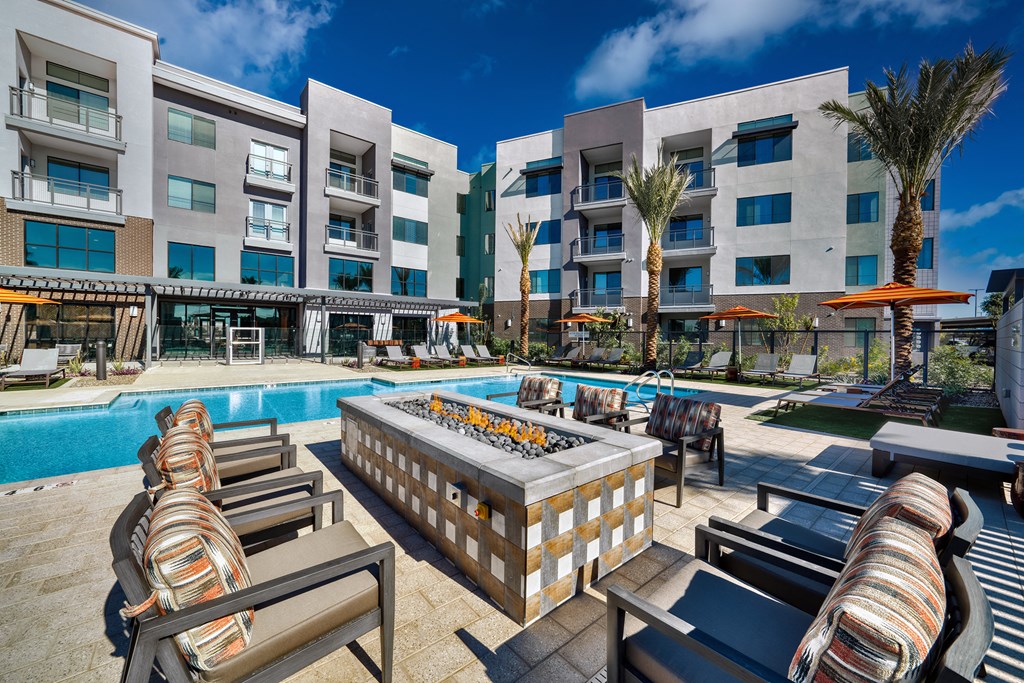 a swimming pool with a fire pit in front of an apartment building