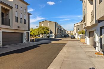 A street view of a residential area with buildings on both sides and a clear blue sky.