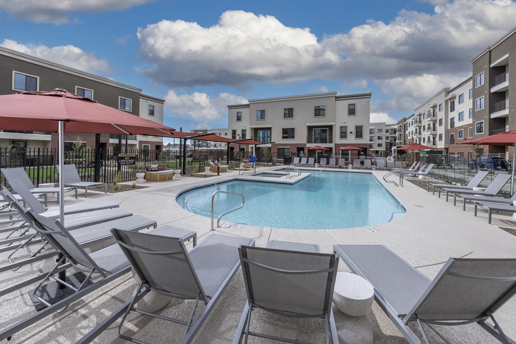 Icon at Cooley Station- a swimming pool with lounge chairs and umbrellas in front of a building