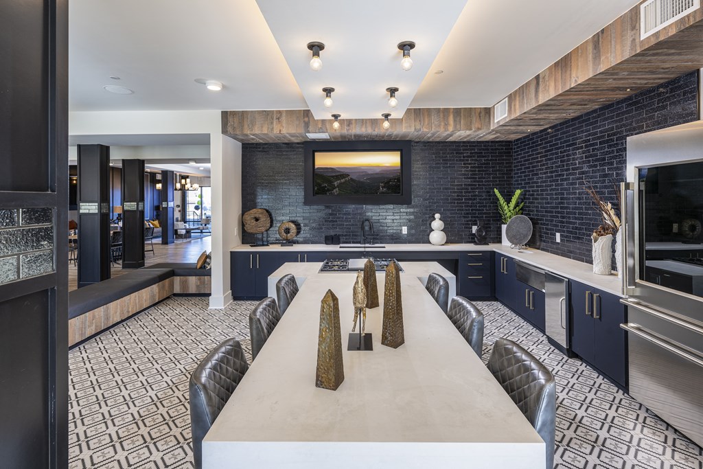 Icon at Cooley Station-Clubhouse with a long white table in a kitchen with blue cabinets