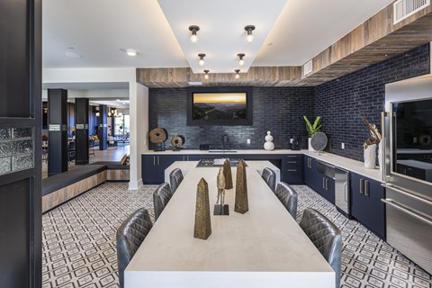 a long dining table in a kitchen with blue cabinets and a television