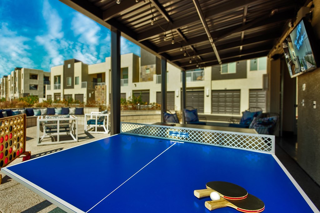 A blue ping pong table with two paddles on it.