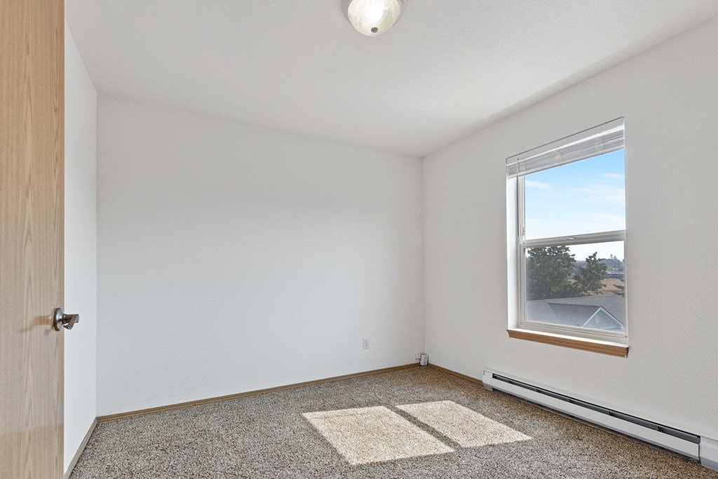 a bedroom with a large window and a carpeted floor