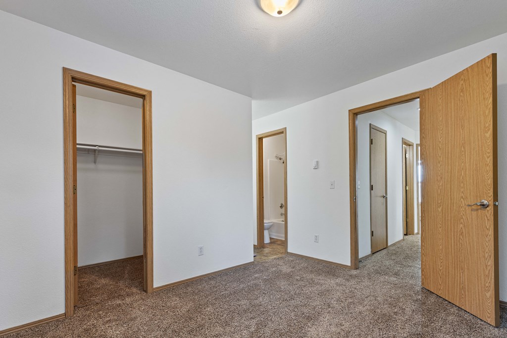 a bedroom with three doors and a carpeted floor