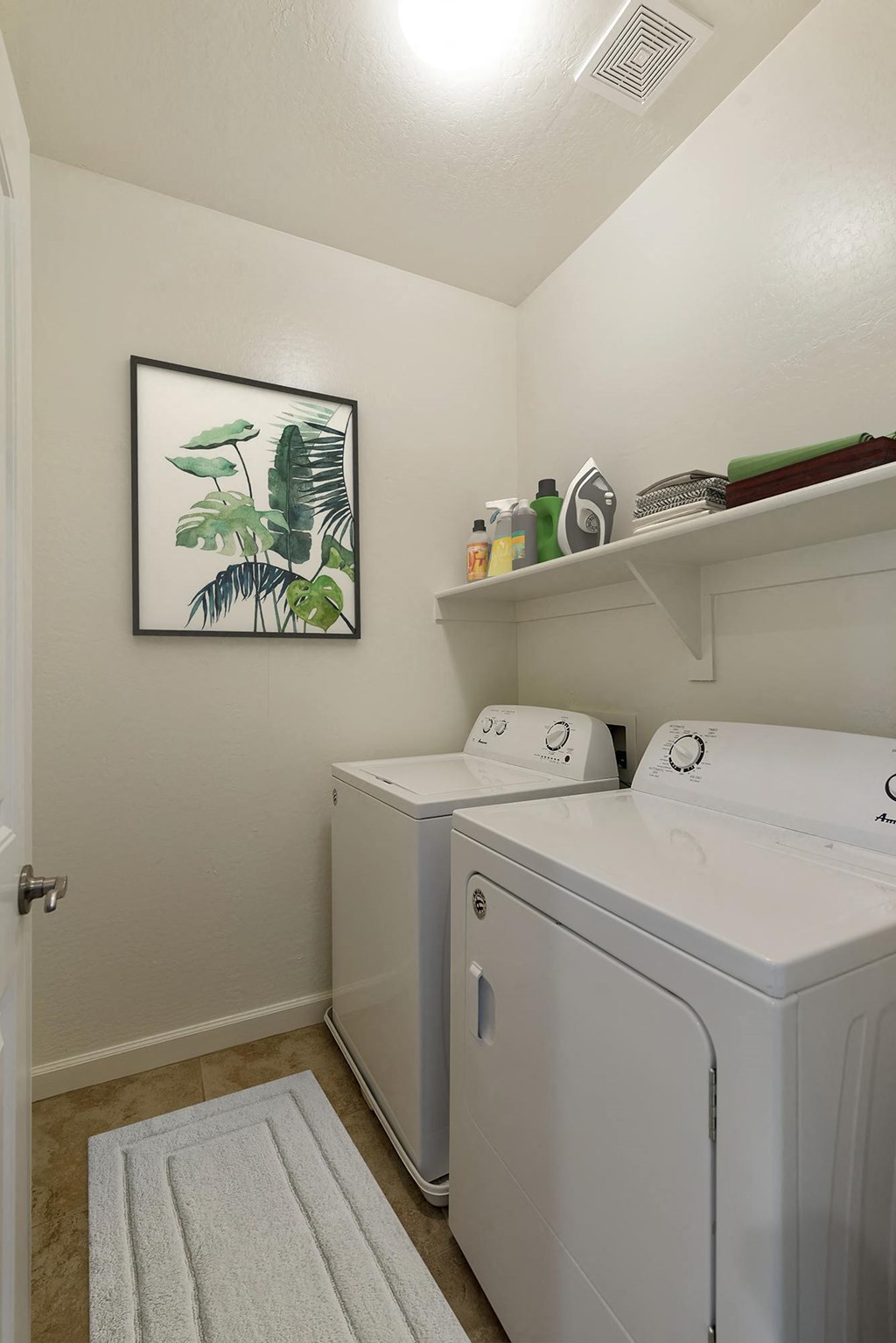 Washroom showing a clothes washer and clothes dryer along with shelf with laundry detergent and folded clothes