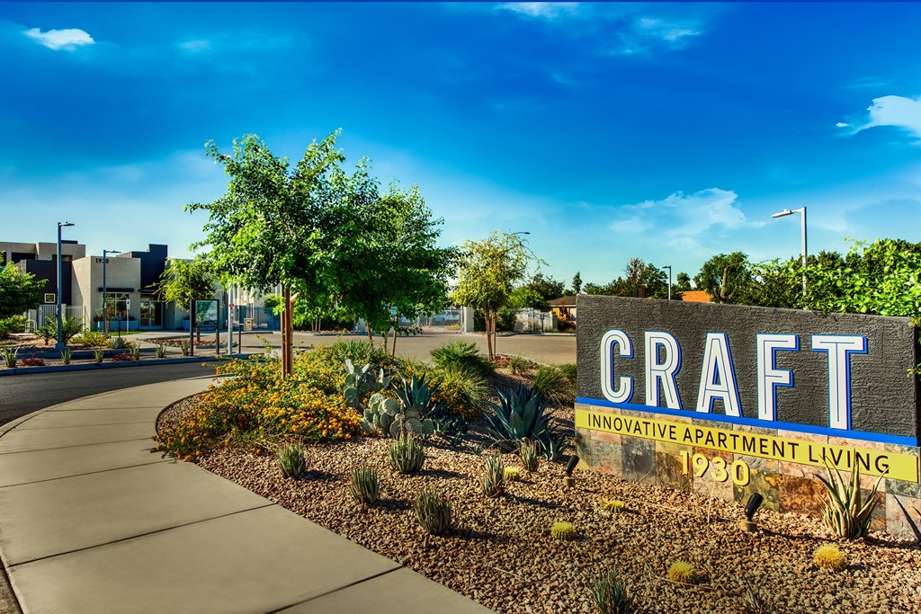 A sign for Craft Apartment Living stands in front of a building.