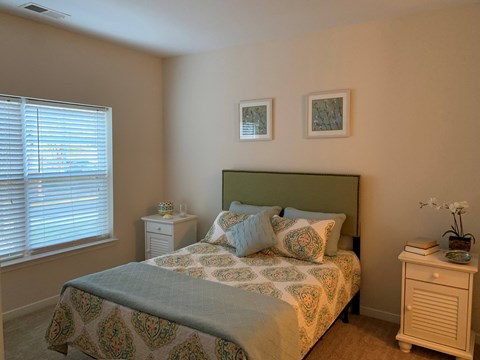 A bedroom with a bed, nightstand, and window.