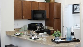 A kitchen with brown cabinets and a black microwave.
