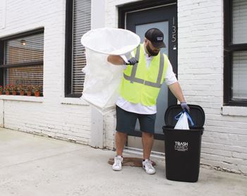a man throwing a large piece of paper into a trash can