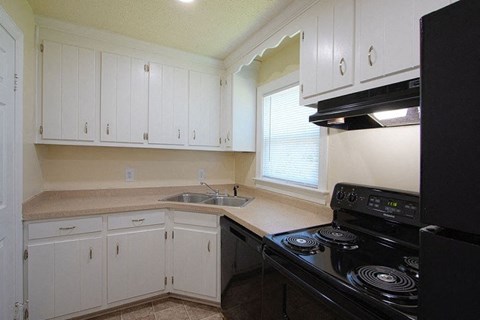 A kitchen with black appliances and white cabinets.