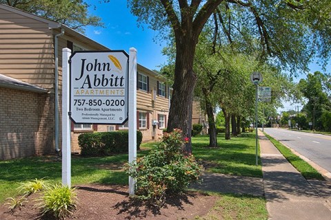 A sign for John Abbitt Apartments is displayed in front of a building.
