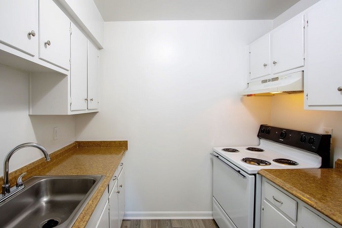 A kitchen with white cabinets and a stove top oven.