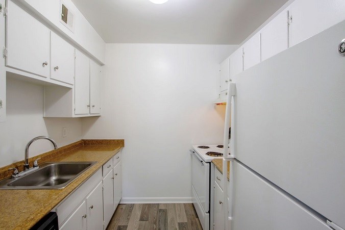 A kitchen with white cabinets and a sink.