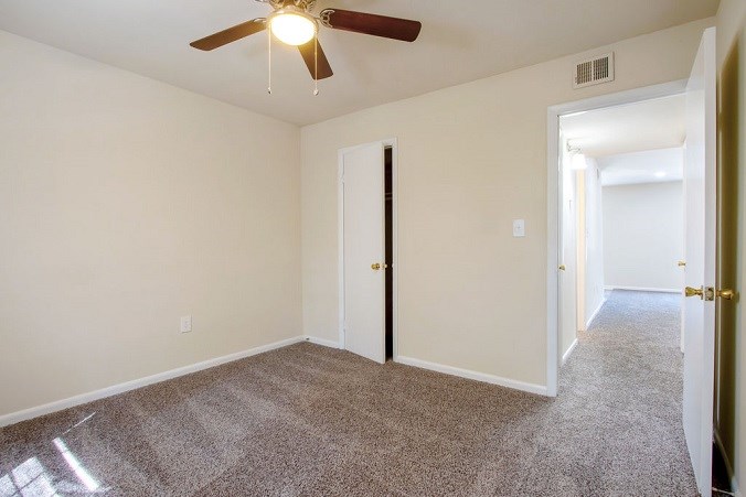 A room with a ceiling fan and carpeted floor.