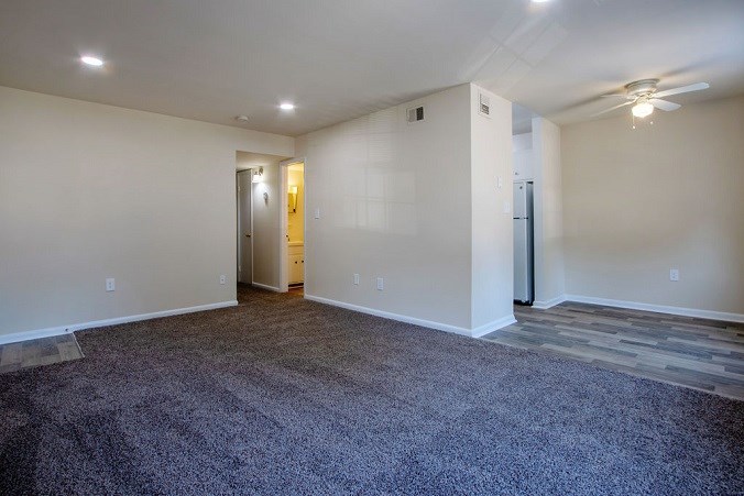 A spacious room with a carpeted floor and a doorway leading to another room.