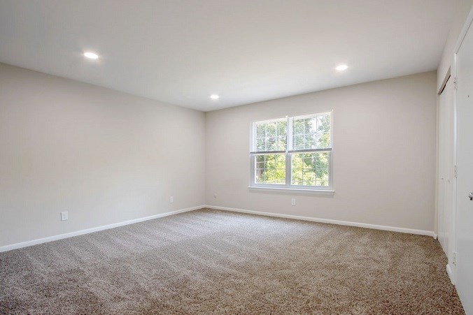 A room with a carpeted floor and a window.