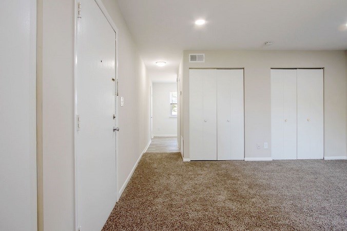 A room with white doors and carpeted floor.