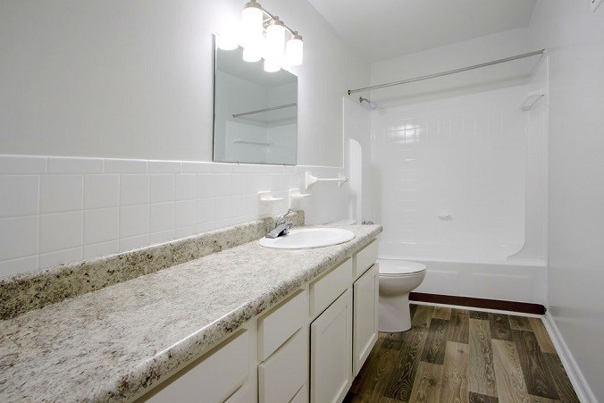A bathroom with a marble countertop and white walls.