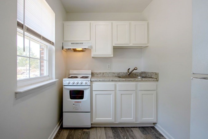 A kitchen with white cabinets and a stove top oven.
