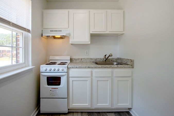 A white kitchen with a stove and sink.