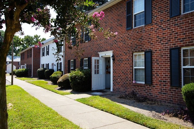 A row of houses with a sidewalk in front.