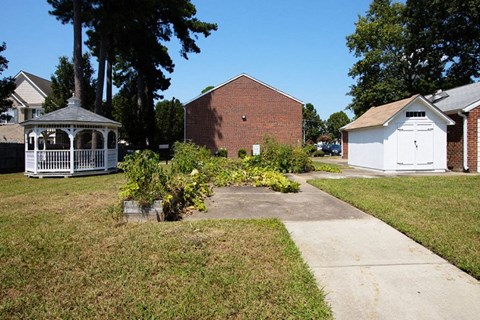 A white gazebo is in the middle of a grassy area.