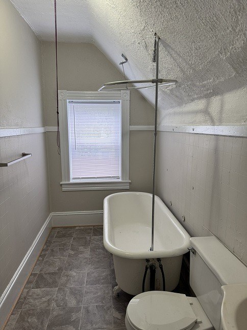 A white toilet sits in a bathroom next to a bathtub.