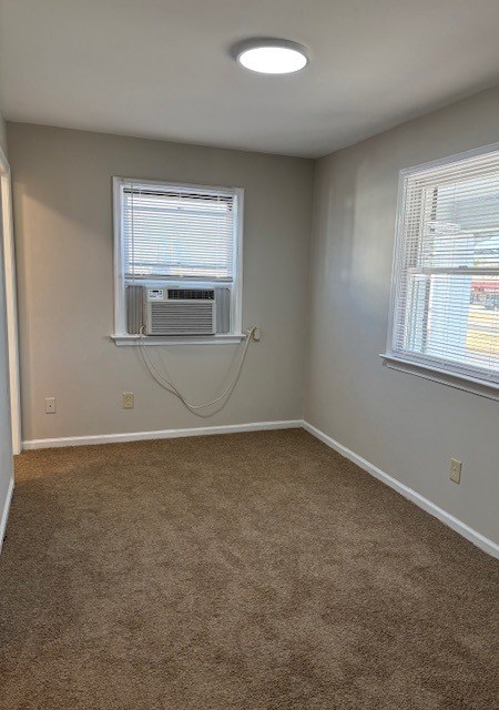 A room with a carpeted floor and a window with blinds.