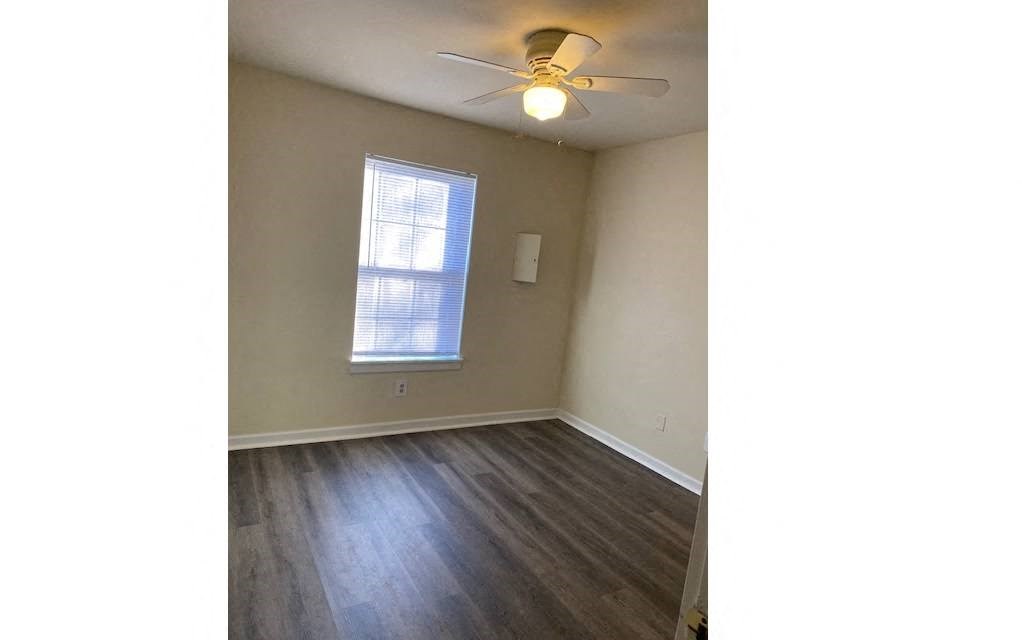 an empty living room with a ceiling fan and a window