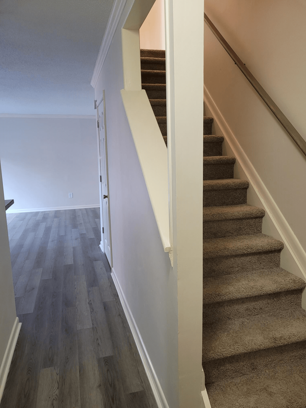 a view down the stairs in a home with wood floors and white walls