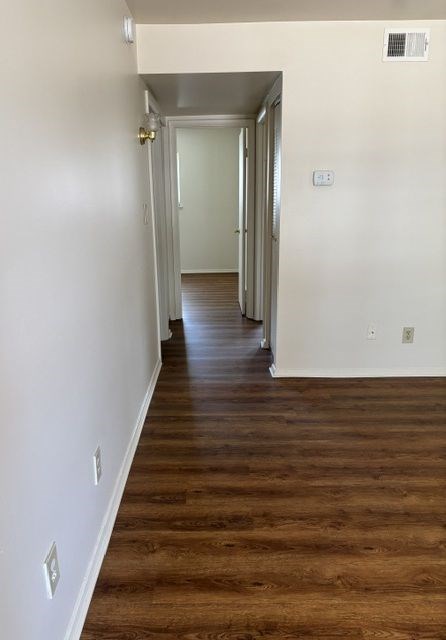 A long hallway with wood floors and white walls.
