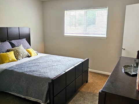 a bedroom with a bed and a desk and a window