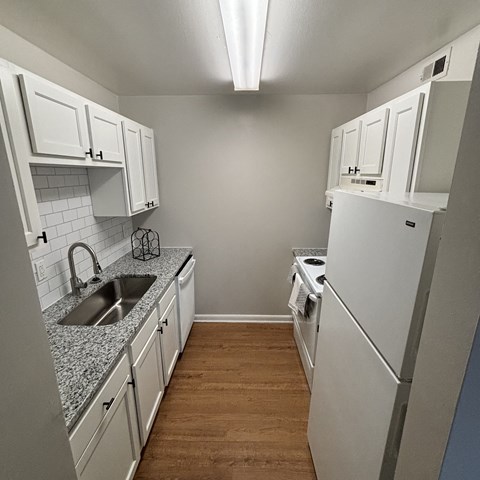 a kitchen with white cabinets and a sink and a refrigerator