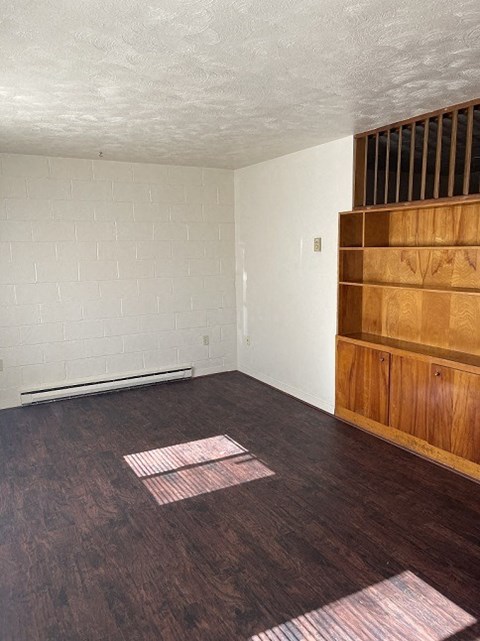 an empty living room with wooden floors and white walls