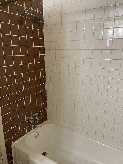 a bathroom with a white tub and a brown tiled wall