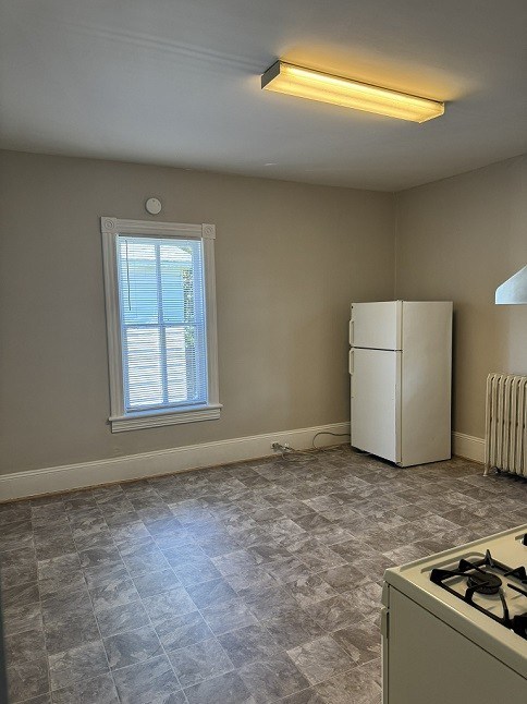 A kitchen with a white fridge and a gas stove.