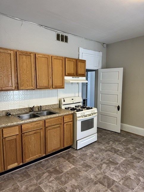 A kitchen with wooden cabinets and a white stove top oven.