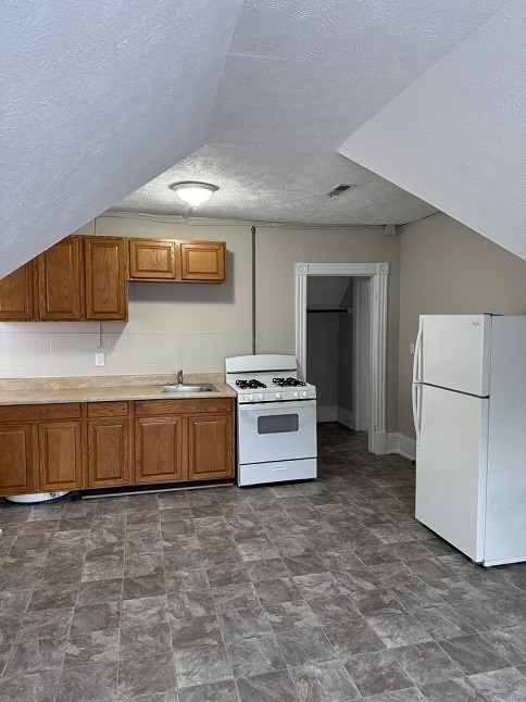 A kitchen with a white stove and refrigerator.