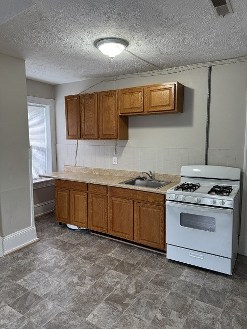 A kitchen with a white stove and wooden cabinets.