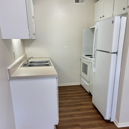 A small kitchen with a sink, stove and refrigerator.