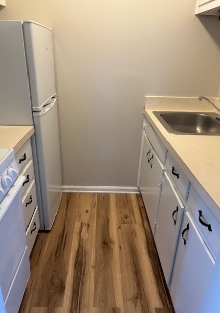 A kitchen with white cabinets and a white fridge.