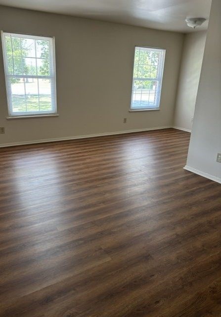 A room with wooden floors and two windows.